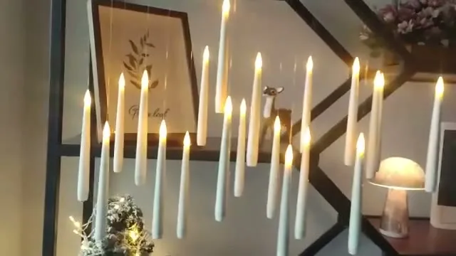 Kilkanaście świec LED Migotka unosi się na żyłce i migocze ciepłym światłem na stylowym regale