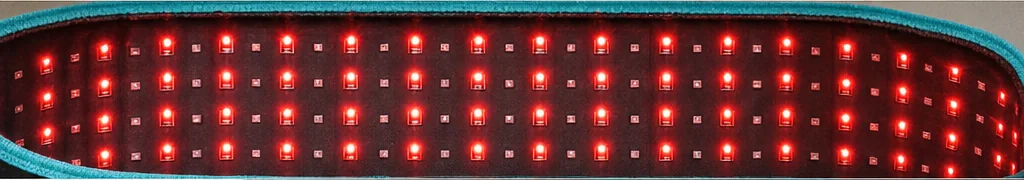 Makro wewnętrznej strony opaski: regularna siatka małych kwadratowych diod świecących na czerwono w równych rzędach, wzdłuż krawędzi biegnie wąska turkusowa lamówka