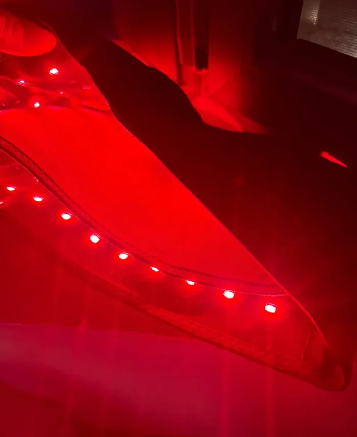 Nieprofesjonalne, nocne zdjęcie telefonem: rozłożona opaska z widocznym rzędem małych kwadratowych czerwonych diod, całe ujęcie zalane czerwonym światłem