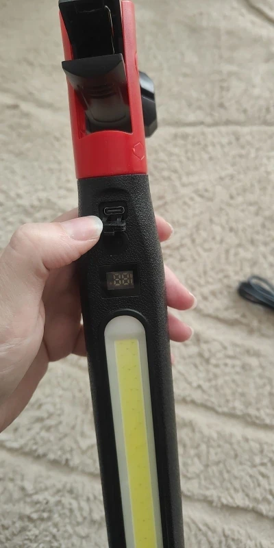 Zdjęcie kupującego: dłoń trzyma lampę przy porcie USB-C i wyświetlaczu poziomu naładowania, niżej widać okno światła