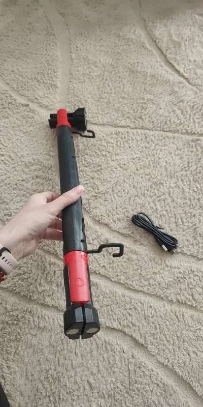 Zdjęcie kupującego: lampa trzymana w dłoni na jasnym dywanie, przy czerwonym kołnierzu widać wyłożony hak, obok kabel USB