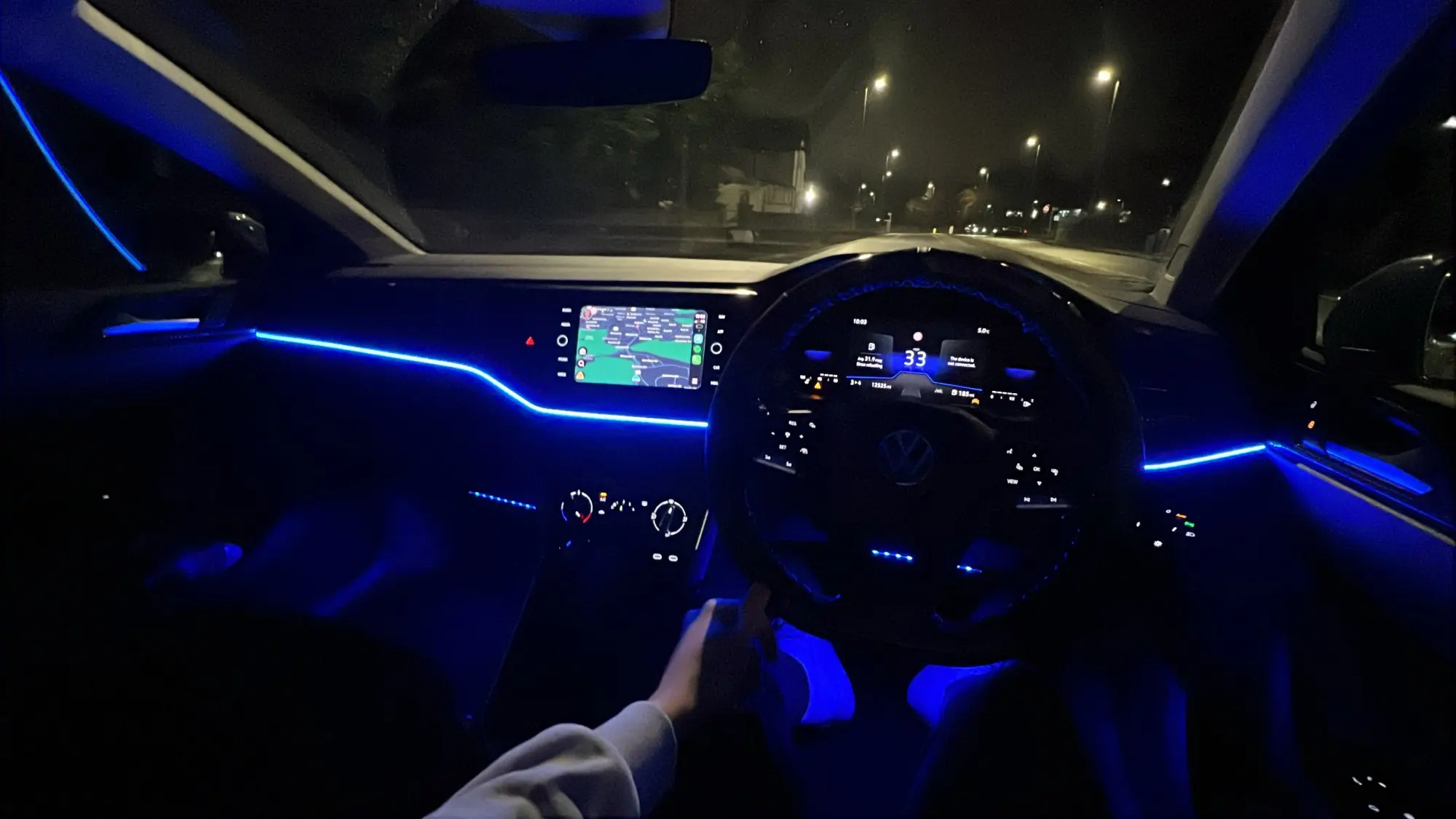 Nocne wnętrze auta z niebieską poświatą wzdłuż deski